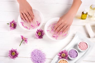 Kısmi Banyo için çivi çiçekler, renkli deniz tuzu, Krem Konteyner ve aroma yağ şişeleri ile masada güzellik salonunda alma kadın görünümünü 