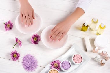 kadının güzellik salonunda banyo için çivi çiçekler, renkli deniz tuzu, Krem Konteyner, aroma yağ şişeleri ve tırnak cilaları ile masada alma kırpılmış görüntü 