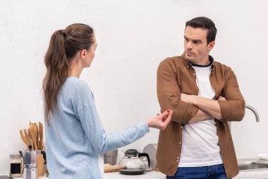 mad adult couple having argument at kitchen clipart
