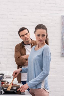 angry adult man looking at wife while she ignoring him after argument at kitchen clipart