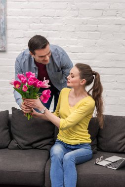 yakışıklı yetişkin adam karısı o evde kanepede oturan ise lale buketi sunulması