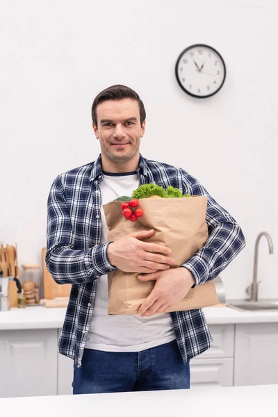 Sonriente Hombre Adulto Llevando Bolsa Supermercado Cocina Mirando Cámara — Foto de stock gratis