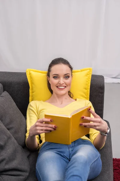 Ευτυχισμένη Ενήλικη Γυναίκα Διαβάζοντας Βιβλίο Στον Καναπέ Στο Σπίτι Και — Φωτογραφία Αρχείου