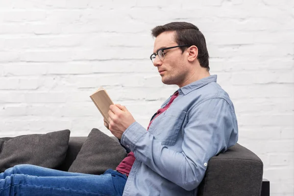 Focused Adult Man Reading Book Couch Home — Stock Photo, Image