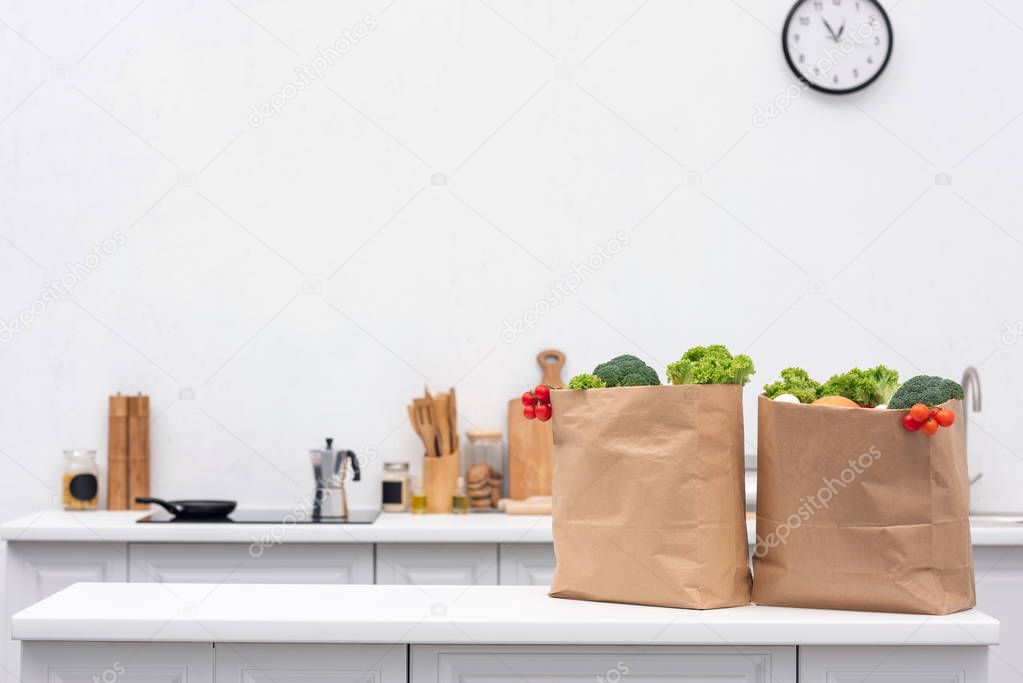 grocery store bags with vegetables on table at kitchen