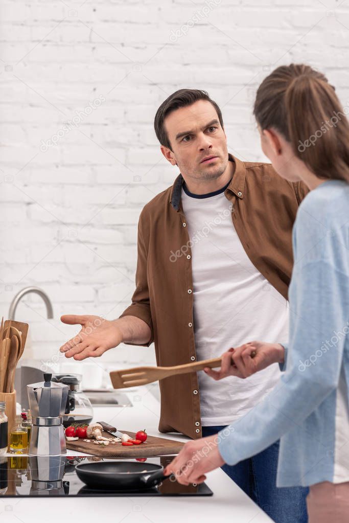 adult couple having argument at kitchen suring while preparing dinner