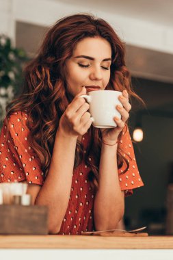 güzel bir kadın portresi göz kapalı tutarak kafede elinde aromatik kahve fincan ile