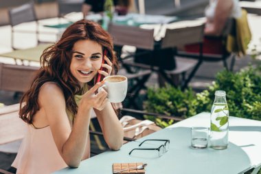 gülümseyen kadın portresi ile smartphone kafede konuşurken kahve