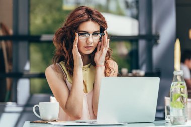 kafede dizüstü bilgisayar üzerinde çalışan gözlük içinde genç blogger portresi