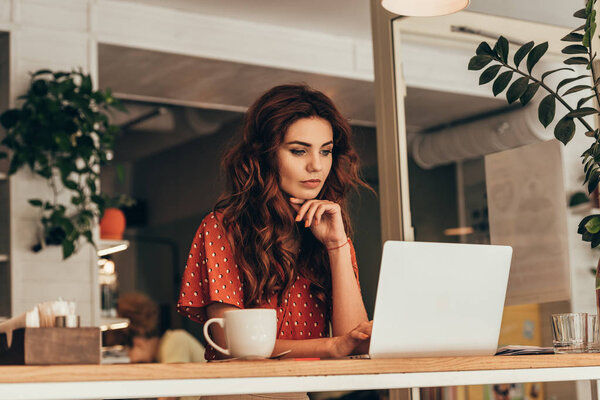 портрет молодого блогера, работающего на ноутбуке в кофейне

