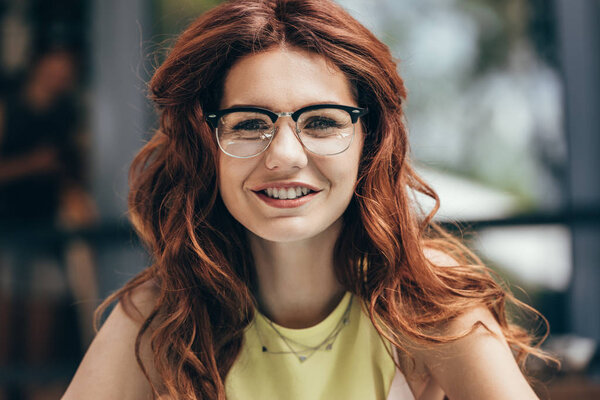 portrait of beautiful smiling woman in eyeglasses looking at camera