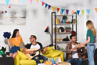 Gençler pizza ile gülümseyen, bira ve evde birlikte eğleniyor gitar parti 