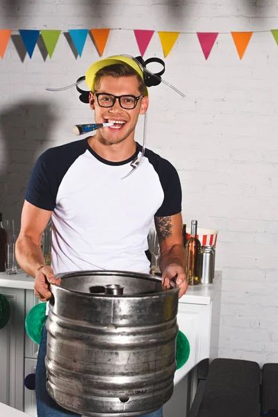 stock image happy young man in beer hat holding keg of beer and smiling at camera