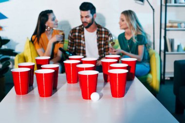 plastik bardak ve bira pong ve genç arkadaşı arkasında şarap içmek için topu yakından görmek