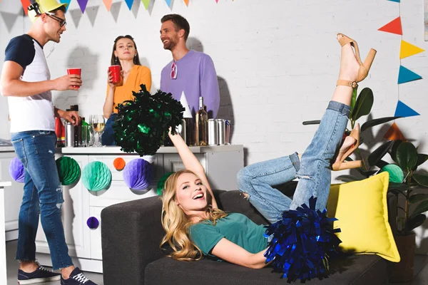 Feliz Jovem Deitado Sofá Enquanto Amigos Alegres Festa Atrás — Fotografia de Stock