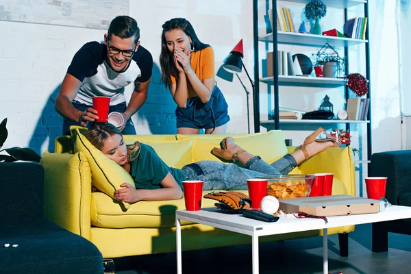 Laughing Young People Looking Drunk Female Friend Sleeping Sofa Home — Stock Photo, Image