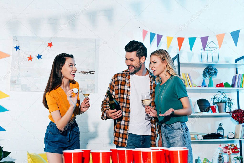 happy young friends playing beer pong at home party 