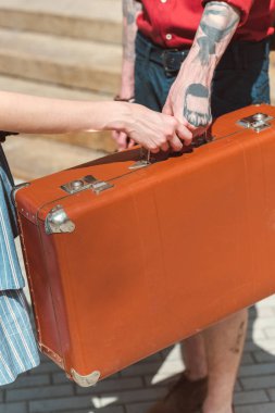 partial view of couple holding retro travel bag clipart