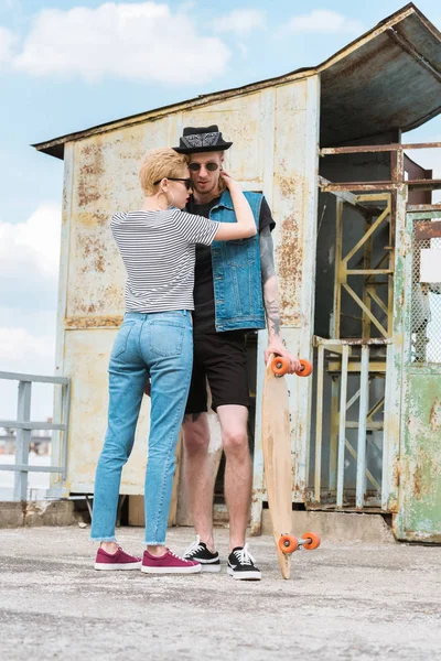 Stylische Freundin Umarmt Tätowierten Freund Mit Skateboard — kostenloses Stockfoto