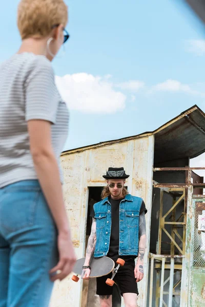 Lage Hoekmening Van Vriendje Met Tatoeages Skateboard Stijlvolle Vriendin Kijken — Gratis stockfoto