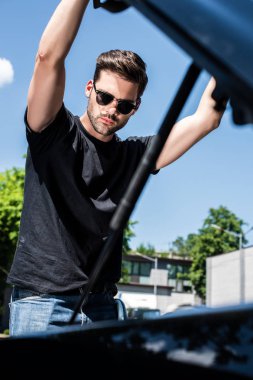 Street kaput açma güneş gözlüklü genç adamın düşük açılı görünüş