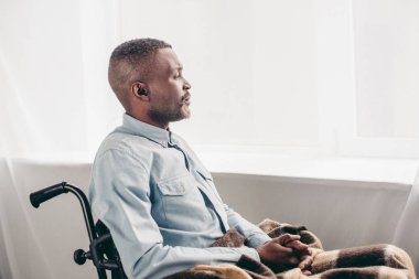 side view of senior african american man sitting in wheelchair and looking away
