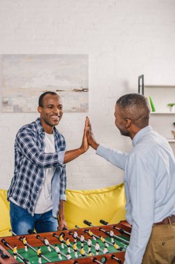 Baba ve oğul oynarken yüksek beş veren futbol birlikte evde masa