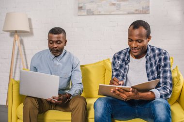 komuta sizde dizüstü ve Yetişkin oğlu evde not defterinde yazılı kullanma