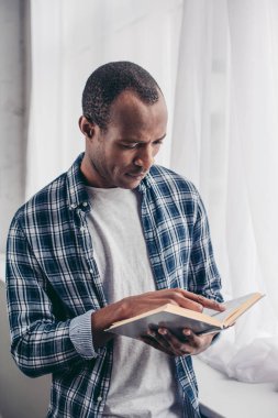 odaklı genç Afro-Amerikan adam ayakta ve kitap okuma