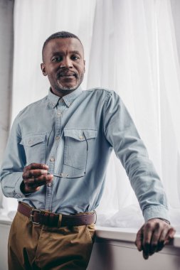 Gözlük tutan ve kameraya gülümseyen kıdemli Afro-Amerikan yakışıklı