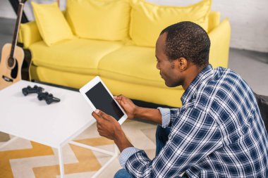Afro-Amerikan adamın evde boş ekran ile dijital tablet kullanarak yüksek açılı görünüş