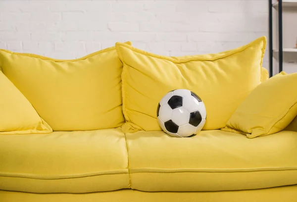 soccer ball on yellow couch in cozy room