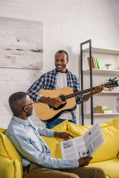 Heureux Homme Âgé Avec Journal Fils Adulte Avec Guitare Souriant — Photo gratuite