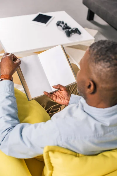 Vista Alto Angolo Anziano Afroamericano Uomo Lettura Libro Mentre Seduto — Foto stock gratuita