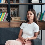 Woman looking at camera while sitting on sofa at home