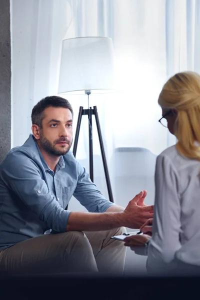 Hombre Haciendo Gestos Hablando Con Consejera Femenina Mientras Ella Escribe — Foto de Stock