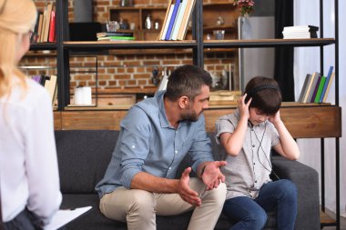 Babam konuşurken kulaklık küçük oğlu için aile terapisi oturum kadın avukat tarafından geniş kollu 