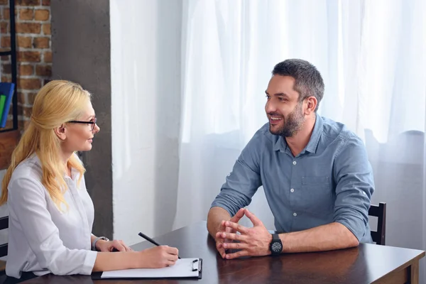 Lächelnder Mann Gespräch Mit Einer Psychiaterin Während Sie Büro Klemmbrett — Stockfoto