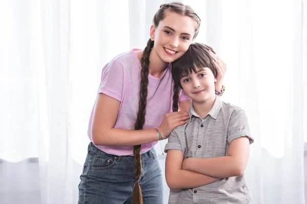 Smiling Teenage Girl Embracing Little Brother Crossed Hands Home — Stock Photo, Image