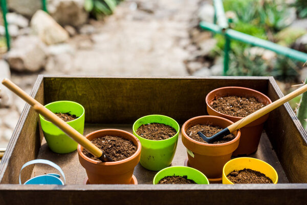 close-up view of box with flower pots, soil and gardening tools 