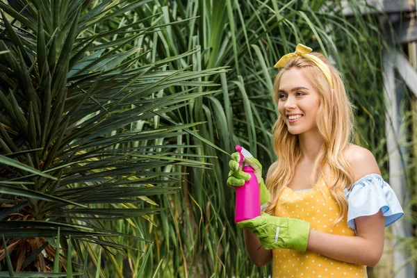 Atraente Sorrindo Mulher Loira Segurando Pulverizador Regando Plantas Verdes — Fotografia de Stock