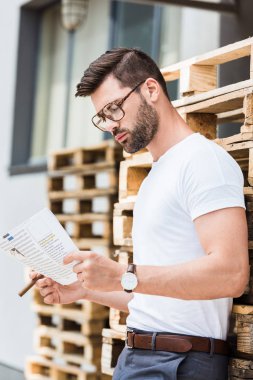 Puro ve ahşap paletleri tarafından ayakta eller belgede yakışıklı sakallı işadamı