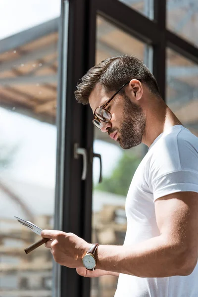 Hombre Confiado Moda Sosteniendo Cigarro Leyendo Informe Por Ventana — Foto de stock gratuita