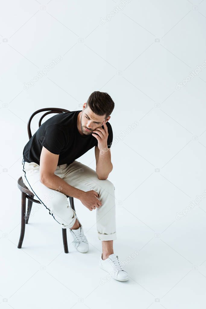 Stylish young man sitting on chair on white background