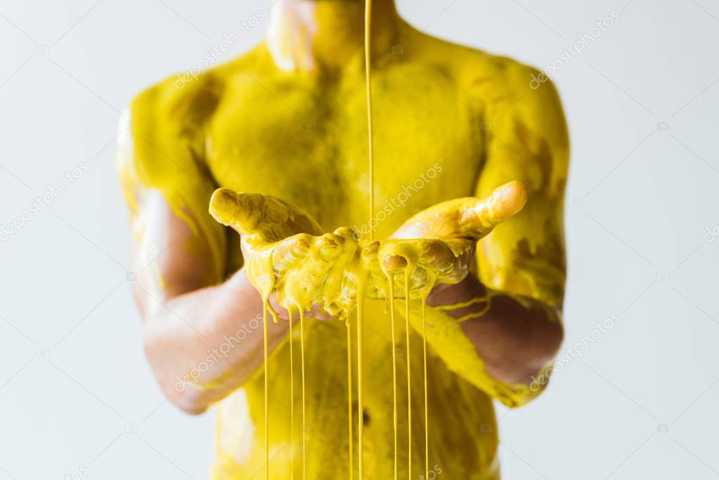 Cropped view of yellow paint pouring on male hands isolated on white background