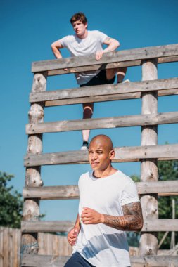 selective focus of young interracial soldiers practicing in obstacle run on range clipart