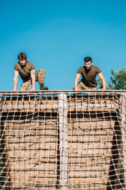 low angle view of young soldiers practicing during obstacle run on range clipart