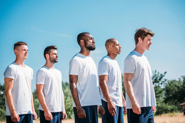 side view of interracial young soldiers standing on range on summer day