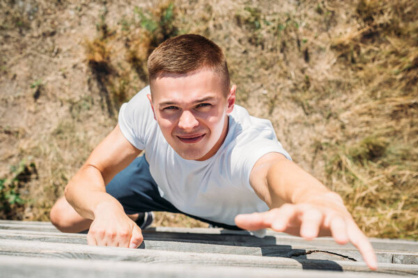 overhead view of young soldier climbing wooden barrier during obstacle run on range