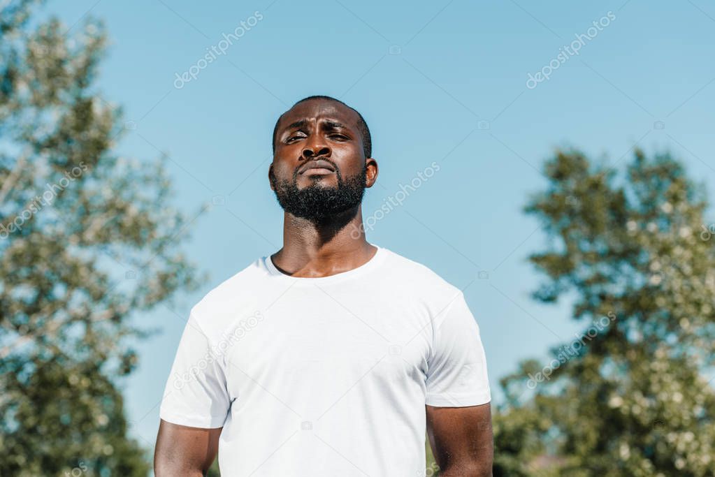 portrait of confident african american soldier in white shirt against blue sky